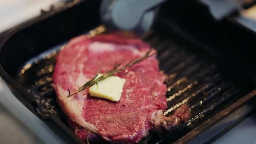 Close up of a juicy steak being moved with a spatula on a hot grill pan
