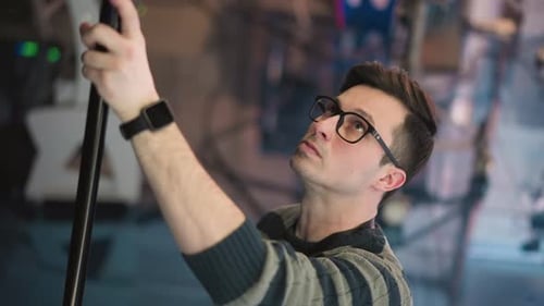 Closeup of Man Adjusting Boom Microphone in Studio Environment During Video Production
