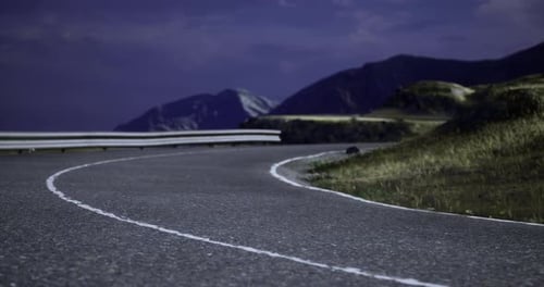 Serpentine Road Winding Through Mountainous Landscape in Twilight Hours