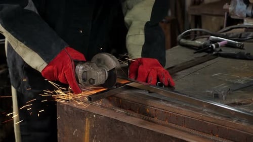 A Man Using Grinder and Cuts Metal in a Forge or at a Metal Production Plant