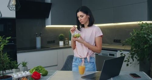Woman Eating Salad in Kitchen