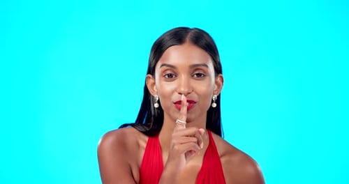 Secret, face and woman with finger on lips in studio, blue background and privacy sign