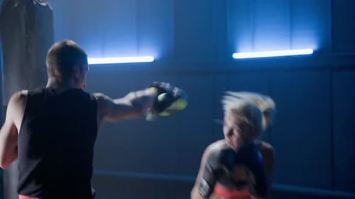 Athletic Woman Training Kickboxing with Trainer in Gym