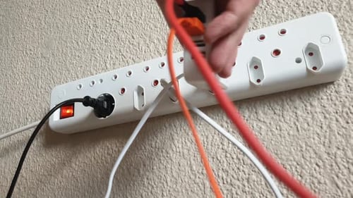 Mão masculina conectando um carregador elétrico de telefone USB e tablet a um aparelho europeu de 220v montado na parede
