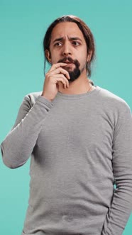 Thoughtful Young Adult Man Ponders on Light Blue