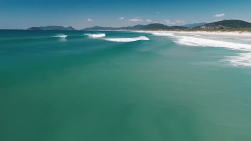 Brazilian beach aerial. Flight forward over the sea surface with perfect waves