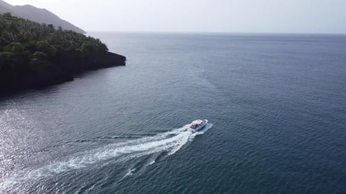 Isolated motorboat leaves white wake trail over blue and calm sea water at Samana bay in Dominican