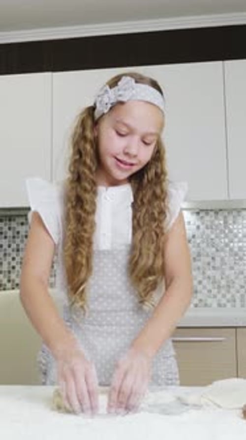 Young Girl with Long Hair is Happily Baking in a Modern Kitchen Preparing Dough for Pastries
