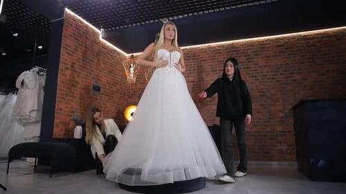 Noiva loira alta e elegante experimentando um vestido de noiva em uma boutique de noivas