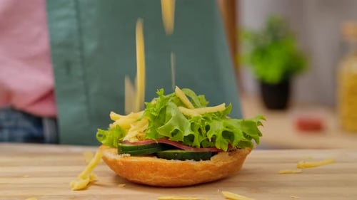 Cheese Being Sprinkled on Vegetarian Sandwich on Wooden Board