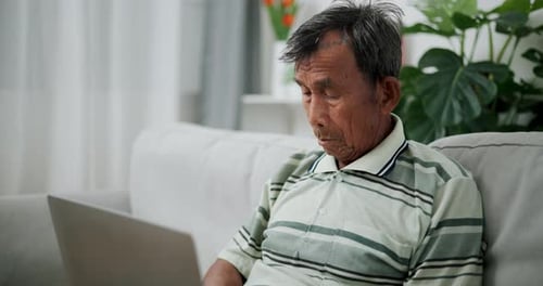 Senior man using a laptop in living room