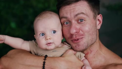 Handsome Caucasian man holding an infant child close to his face.