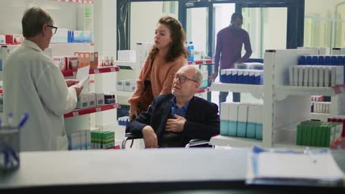 Pharmacist Consults with Mature Man in Wheelchair