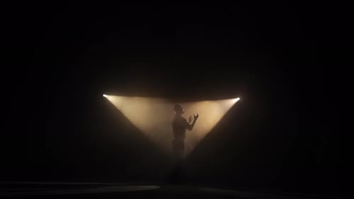 Hombre con sombrero actuando en el escenario a la luz de los focos