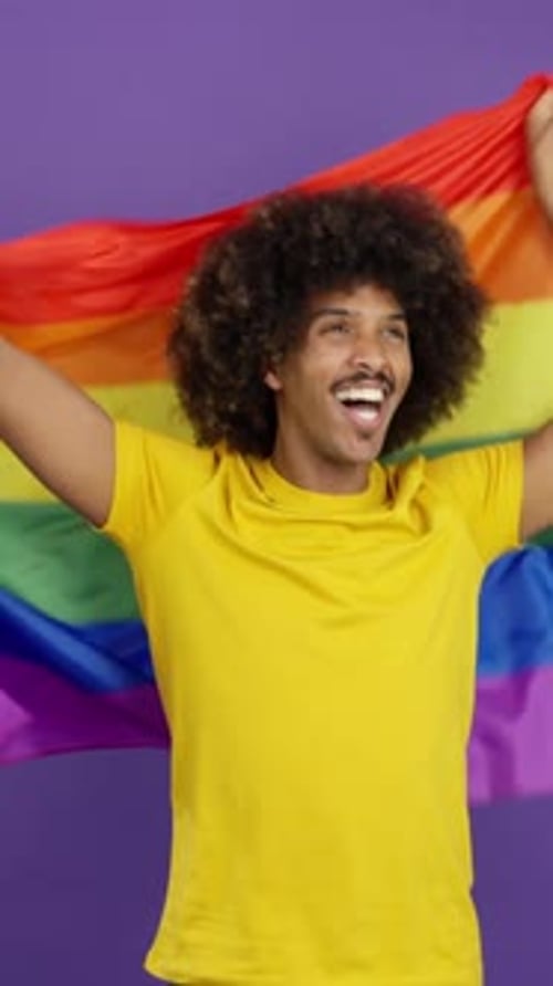 Person Smiles and Waves Rainbow Flag
