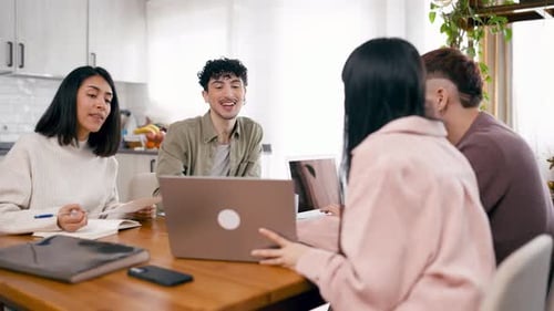Young Adults Collaborating Around a Wooden Table at Home