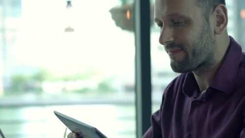 Young Man with Tablet Computer and Drinking Cocktail in Cafe 30s