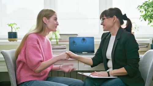 Two Women Talking and Shaking Hands in Office