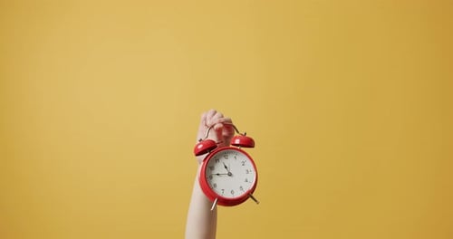 Woman Gesturing with Her Hands with Red Alarm Clock on Yellow Background