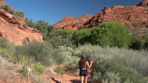 Young Female in Desert Wilderness on Hiking Trail Under Red Rock Sandstone Hills Full Frame Slow Mot