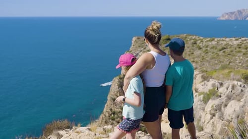 Young Mother And Children Embrace While Enjoying Spectacular View Across Blue Waters