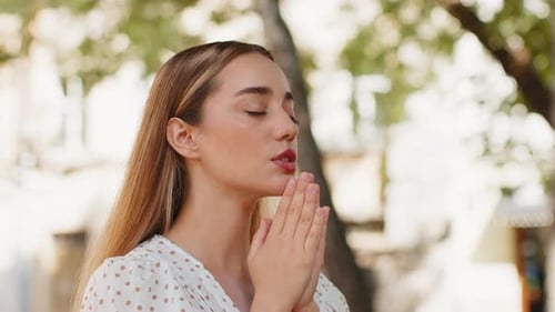 Young Woman Praying Outdoors in City Park