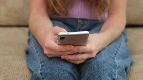 Kid Girl Sitting on Sofa and Holding Mobile Phone Close Up Child Typing Massage