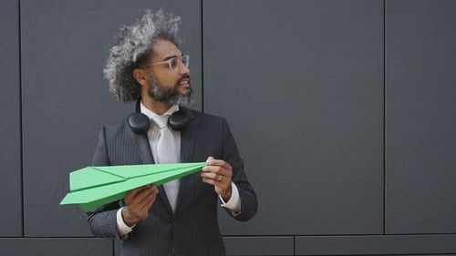 Adult in Suit Holds Green Paper Airplane