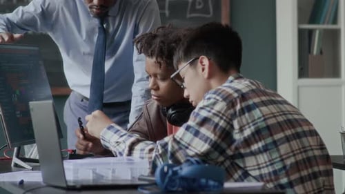 Teacher Assists Students with Coding Project in Classroom