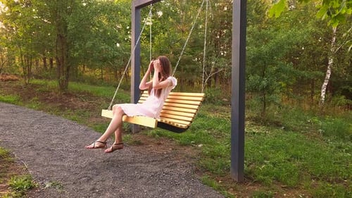 Jolie femme se balançant sur une balançoire dans le parc de la ville