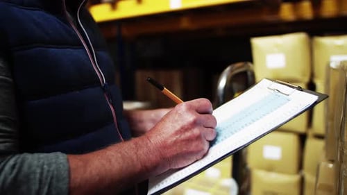 An Unrecognizable Senior Male Warehouse Worker or a Supervisor, Writing