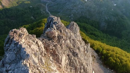 Aerial perspective of rugged mountain peaks piercing through lush forests embodying nature's grandeu