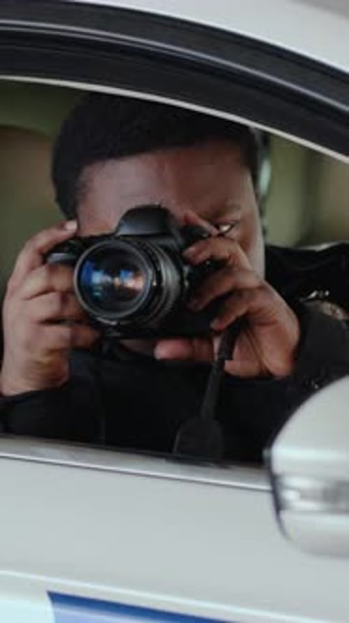 A Police Officer Scans the Area While a Man Films From the Car