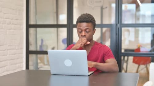 Young Adult Coughing While Working on Laptop