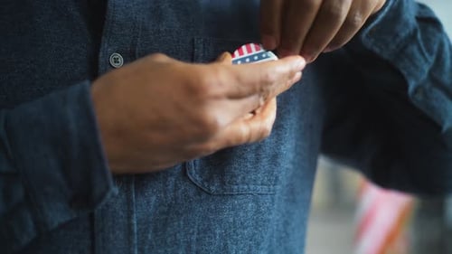 African American US Citizen Puts on Badge with USA Flag Logo