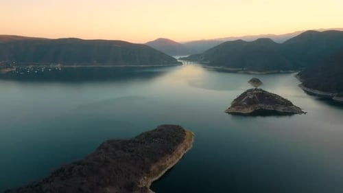 Aerial drone flying over a lake, water dam, with mountains at sunrise. Beautifull dreamy landscape