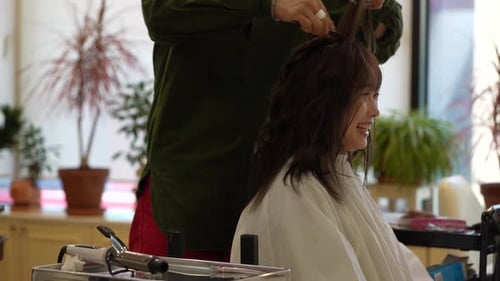 Male hairdresser ironing a woman's hair