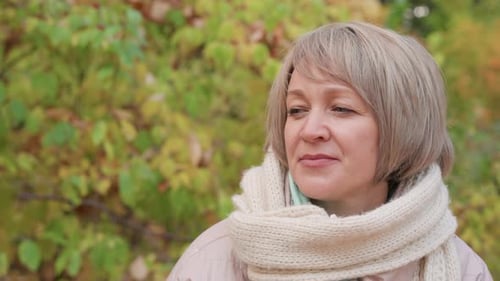 Woman in Scarf Smiling Gently While Looking at Companion in Autumn Park