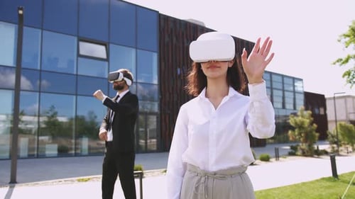 Caucasian Man and Woman in Business Style and VR Headset Standing Outside Modern Glass Building of