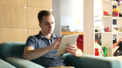 Young Man Using Tablet While Sitting on Couch