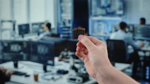 Hands Holding Memory Cards in Modern Office Workspace