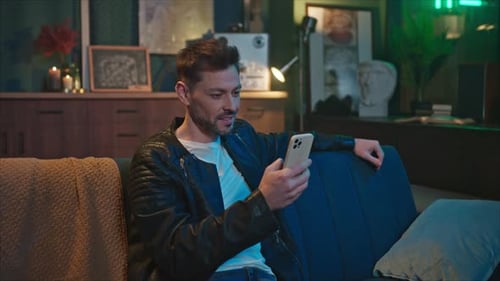 Man Relaxing on Sofa Using Mobile Phone Indoors