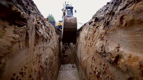 Excavator Burying Trench with Pipes and Wires on Construction Site Closeup View Repair Works