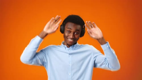 Positive Young African Man Listening to Music with Headphones in Studio