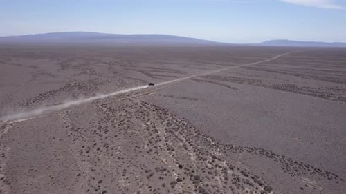 A Black SUV is Driving Fast on a Dusty Road Drone