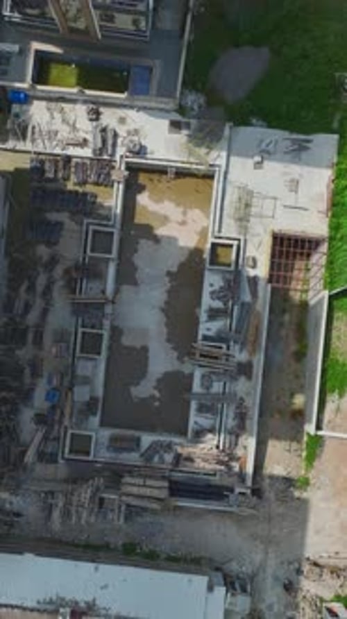 Vertical Drone Footage of Concrete Building Frame with Open Floors and Raw Materials