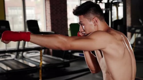Professional muscular sportsman muay thai fighter or kickbox boxer practicing boxing in gym cross tr