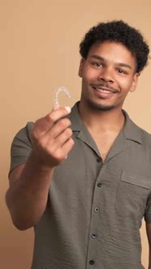 Happy Young Man Showing Invisible Braces in Beige Studio