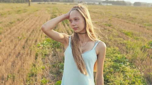 Portrait of a 16 Year Old Girl Standing in the Field at Dusk with Long Hair and a Blue Dress