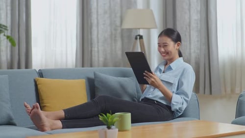 Woman Relaxes on Couch with Tablet